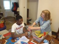 A teacher helping a student build a project from craft materials