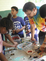 Students and mentors in tie-dye shirts at a hands-on STEM station
