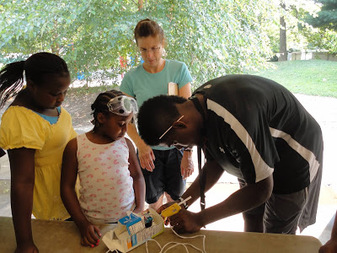 A YES intern helping younger students with a hands-on outdoor activity