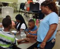 A YES teacher in a blue YES shirt guiding a student through an experiment